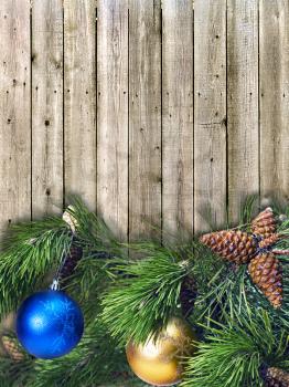 Christmas pine twigs with colored balls on the background of wooden boards