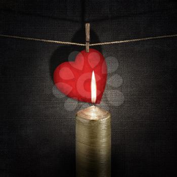 burning candle and red paper heart on a rope over vintage embossed dark backgrounds