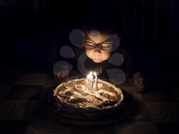 little boy blows out candles on cake