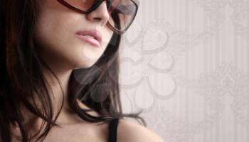 Sexy woman in sunglasses on a floral wallpaper background