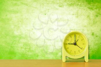 green alarm clock against dirty wall background