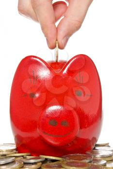 hand putting coin into the red piggy bank