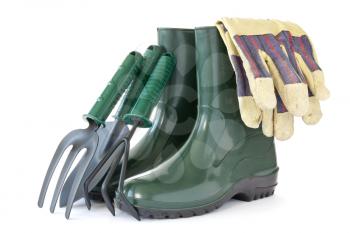  rubber boots with garden tools over a white background