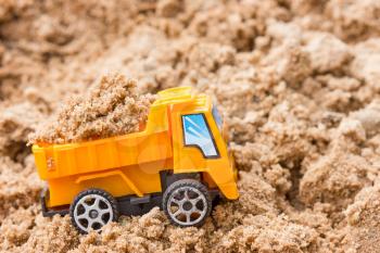 Construction concept. Orange dump truck fully loaded sand