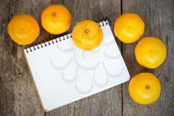 Royalty Free Photo of Clementines and a Notebook on Wood