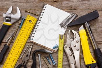Work tools and notebook on the wooden background