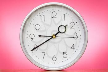 Clock on the table over a pink background