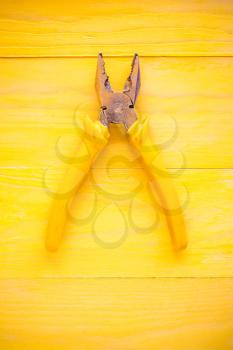 Old pliers on the yellow wooden surface