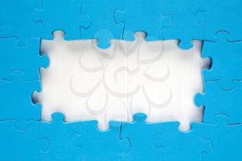 Blue jigsaw puzzle pieces arranged as a border around a wooden surface  with space for your text