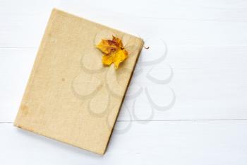 Book and old leaf on wooden background with copy-space