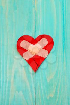 Plaster and paper broken heart on wooden background with copy-space