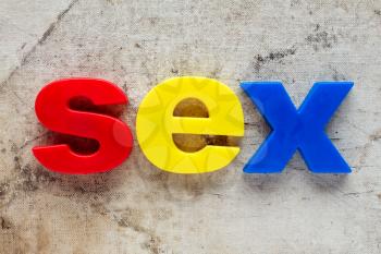 SEX spelled out using colored magnets on dirty background
