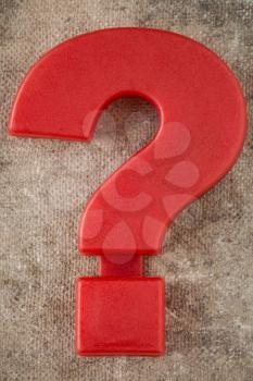 Red plastic question mark on old canvas background