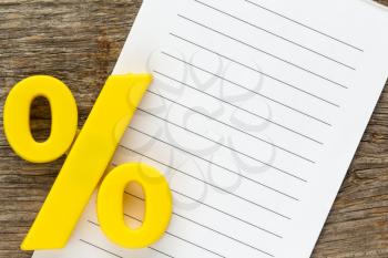 Note paper with yellow  plastic percentage sign