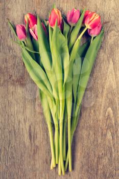 Bunch of beautiful tulip flowers on wooden background. Vintage filter.