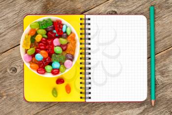 Blank notebook and bowl with mixed candies