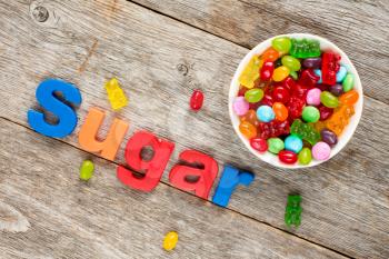
Word SUGAR and bowl of mixed candies ,unhealthy food, reduction of eating sweets