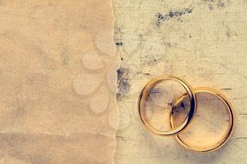 Wedding rings with paper piece on dirty canvas background