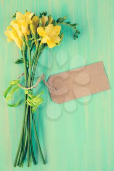 Yellow freesia flowers with blank tag tied with string