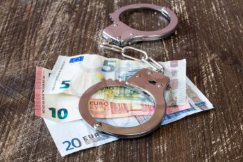 Handcuffs on euro currency, corruption or bribery concept