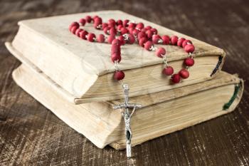 The rosary and old books on wooden background