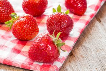Fresh strawberries on red and white checkered napkin.