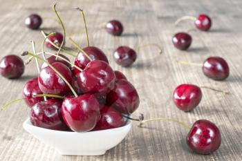 Cherries in white bowl on the wooden surface