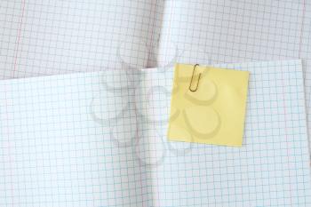 Squared exercise book with blank yellow sticky note