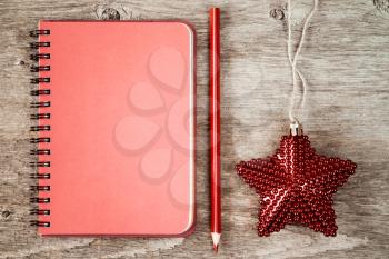 Blank notebook with red pencil and Christmas star on wooden background