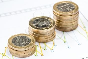 Stack of Euro coin on printed financial diagram. Shallow DOF.
