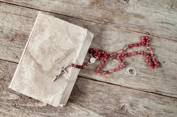 Very old prayer book and rosary on wooden background