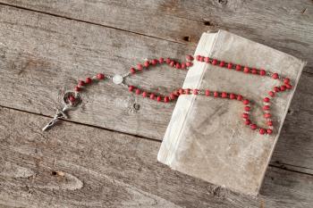 The rosary and old book on wooden background.Top view.
