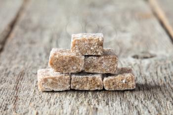 Brown cane sugar cubes on the wooden background
