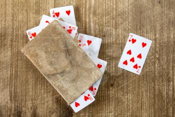 Old book and playing cards on wooden background 