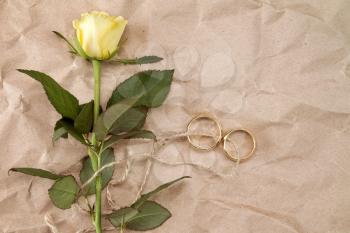   Two gold wedding rings and yellow roses tied with string 