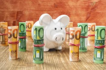 Piggy bank with rolled euro banknotes. Savings or investment concept. 
