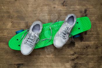 Pair of child sneakers on a green skateboard 