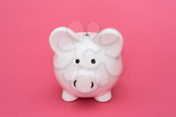 Ceramic piggy-bank on pink background, copy-space