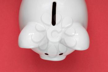 Economy or savings concept with white piggy-bank on red background. Top view.