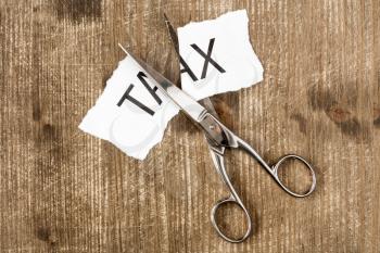 Scissors are cutting a piece of paper with the word tax