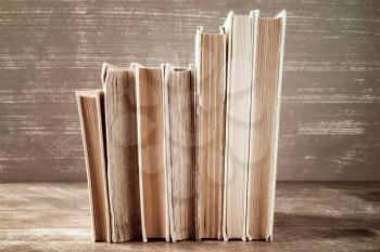 Row of old books stacked on wooden background