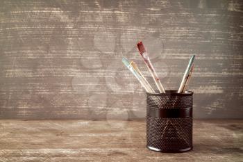 Pot with watercolor brushes on wooden background
