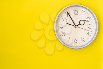  Clock on a yellow wall showing 1:55 o'clock 
