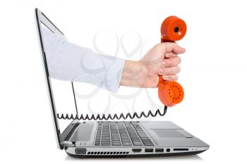 Hand through a laptop monitor giving a orange telephone receiver. Concept for internet phone or customer support