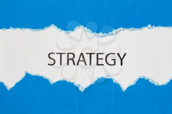 The word STRATEGY appearing behind torn blue paper
