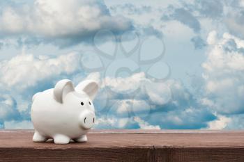 White piggy bank with sky background - business concept