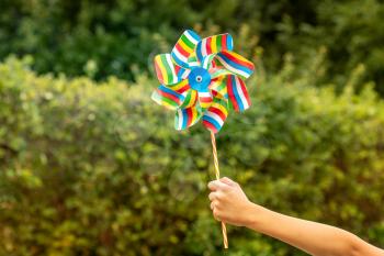 Child holding colorful pinwheel with a trees in background