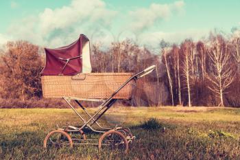 Retro style stroller baby carriage outdoors with autumn landscape