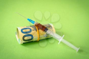 Euro currency with syringe , the concept of addiction, the high cost of medical vaccines.
