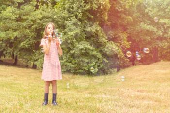 Cute little girl playing with bubbles in a public park